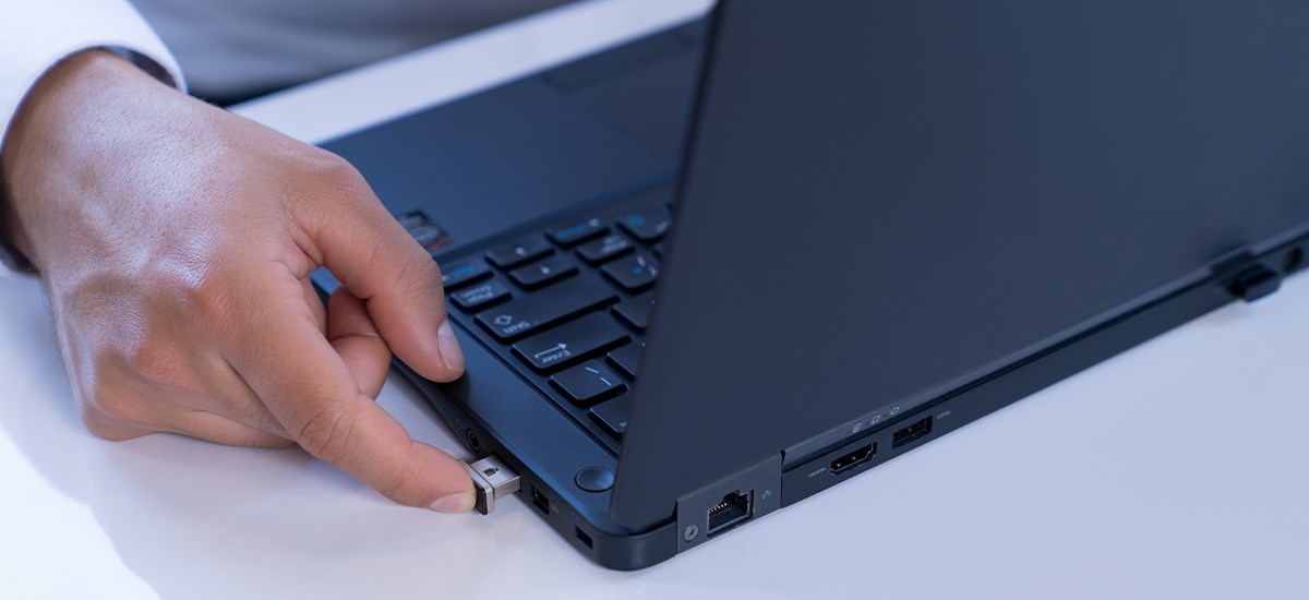 Hand using a physical security key to access a laptop.