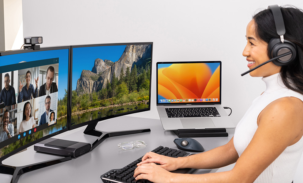 Woman setting up her desktop with Kensington Pro Video Conferencing products.