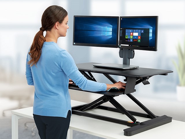 person at sit stand desk with monitor arm