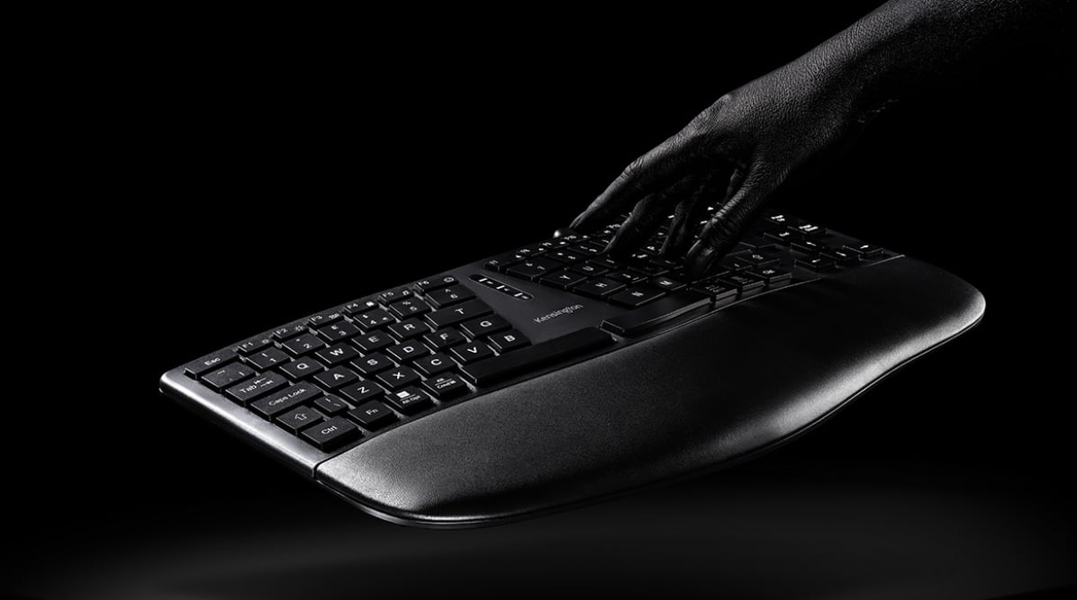 Kensington EQ keyboard on dark background with a hand touching the keyboard Kensington EQ keyboard on dark background with a hand touching the keyboard