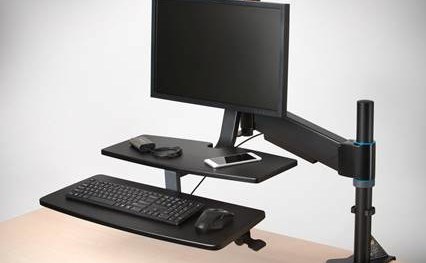 A monitor connected to a ergonomic monitor arm and workstation