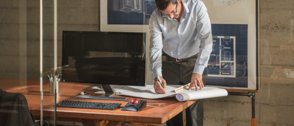 Man standing at a desk and making a note