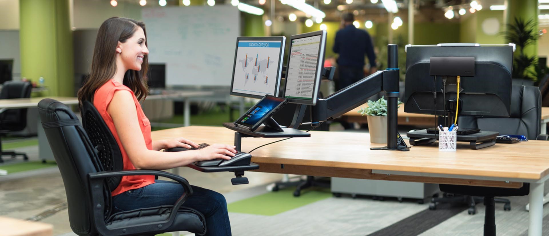 Woman sitting at a dual monitor setup and using a SmartFit® Conform Back Rest