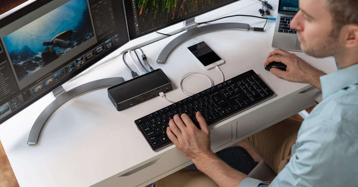 Man working at a dual monitor setup connected to a docking station 