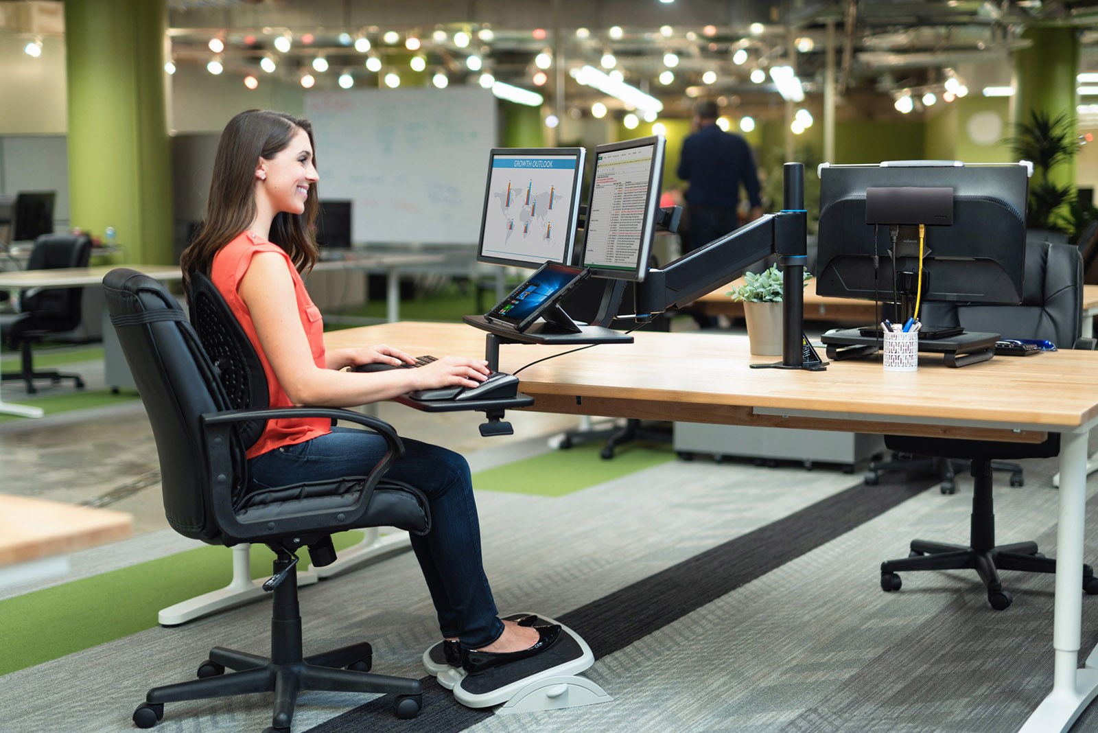 Woman working at a dual monitor setup attached to a monitor arm 