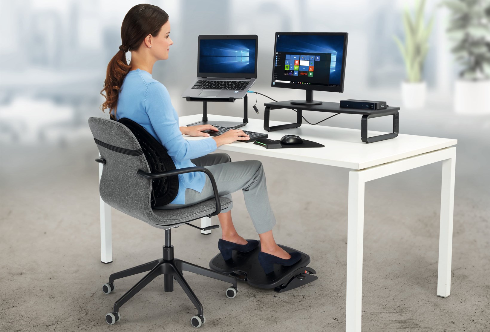 Woman working at a desktop with a monitor and Kensington ergonomic products