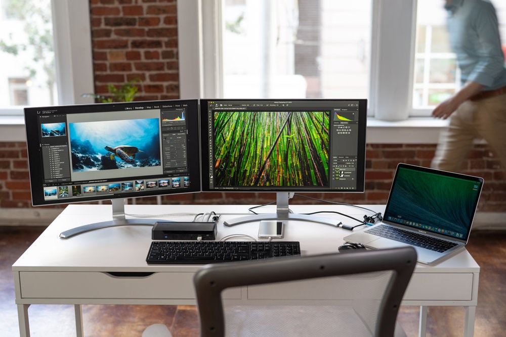 Dual monitors and a laptop connected with a docking station at a desk