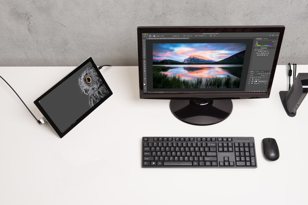 An office desktop space setup with a monitor, tablet, and a docking station