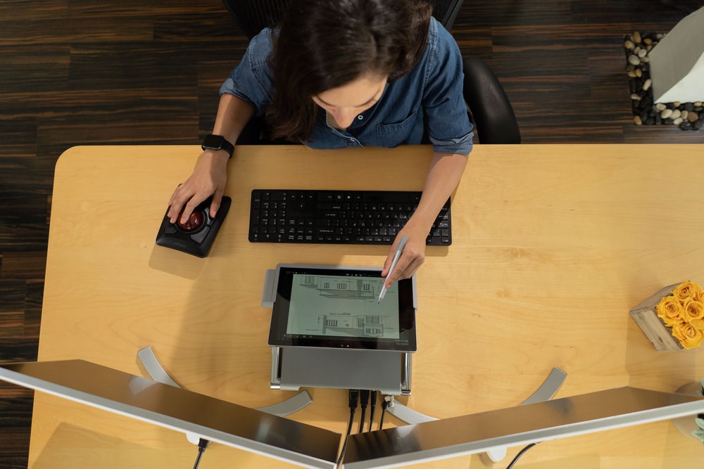 Person using a dual monitor and Surface Pro setup and a trackball mouse