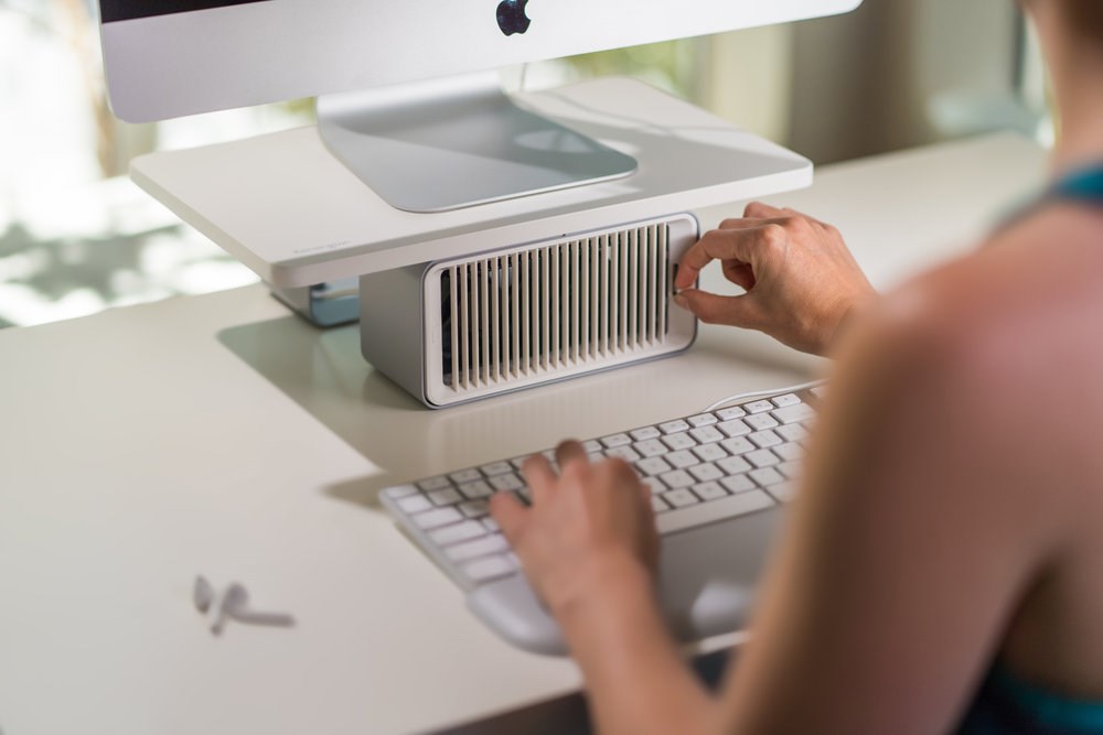 Person typing on a keyboard and adjusting the CoolView Monitor Stand fan setting