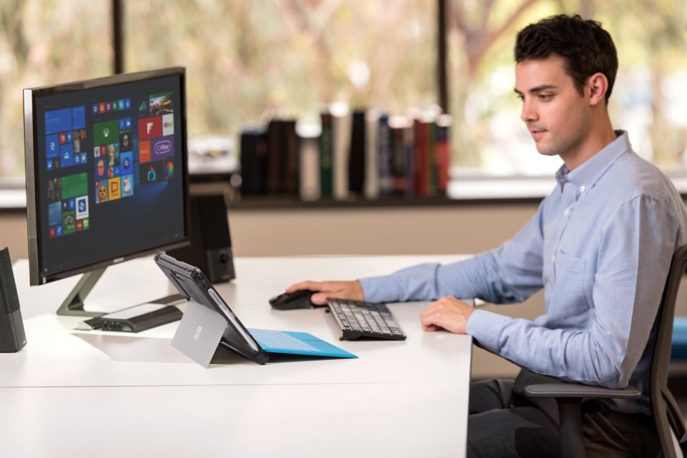 Man using a surface tablet with a desktop monitor