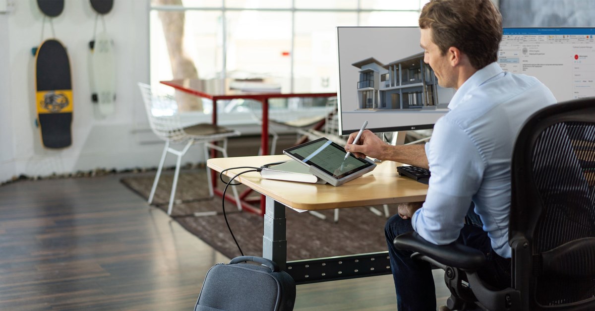 Man working on a Surface Go tablet with a Kensington docking station