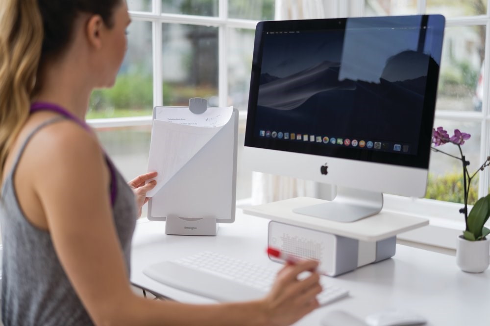 Woman using a Kensington copy holder next to an iMac computer 