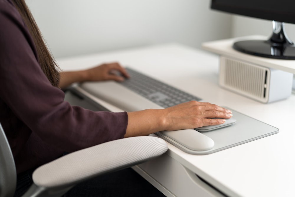 Person using a Kensington keyboard and wrist rest at a monitor