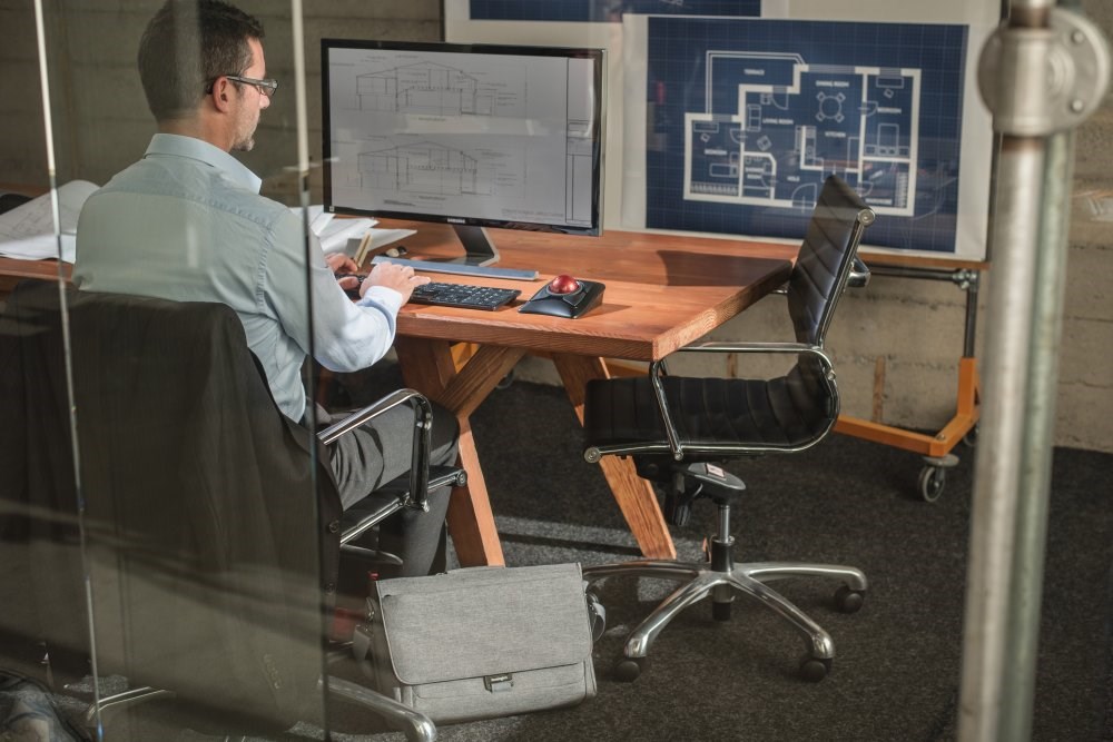 Man sitting at a desktop computer and using a Expert Mouse® Wireless Trackball mouse