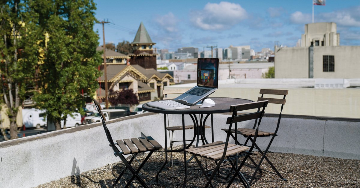 A laptop set up outdoors with a Kensington laptop riser, an ergonomic keyboard, and a vertical mouse