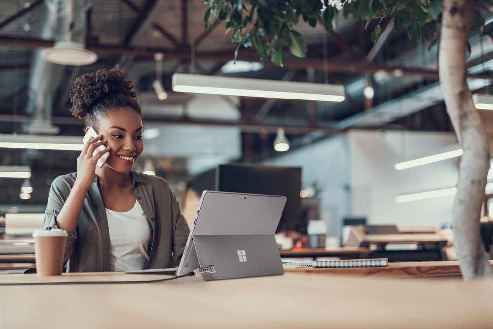 Woman talking on a cellphone and working with a Microsoft tablet connected to a security lock