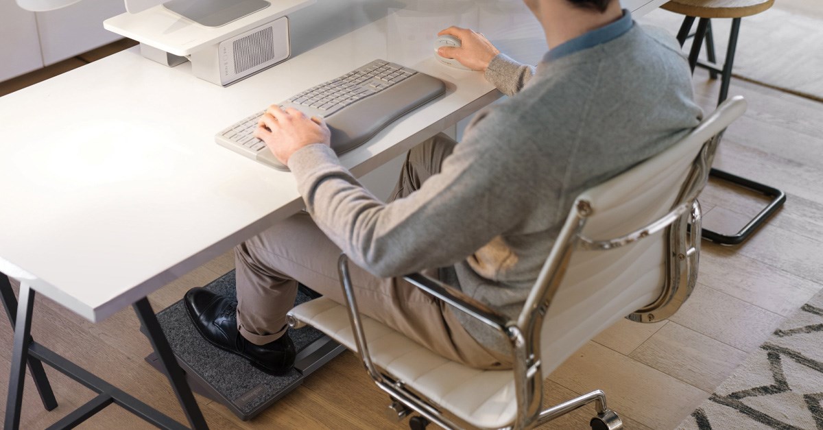 Person sitting at a desk and using a Kensington keyboard and mouse