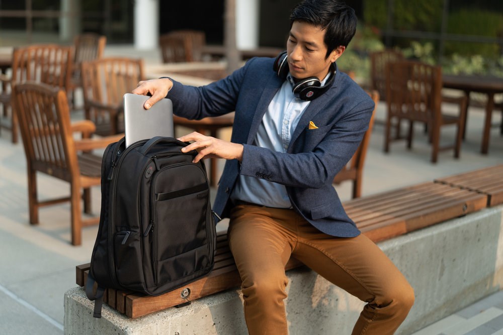 A man putting away a laptop into a Kensington laptop backpack