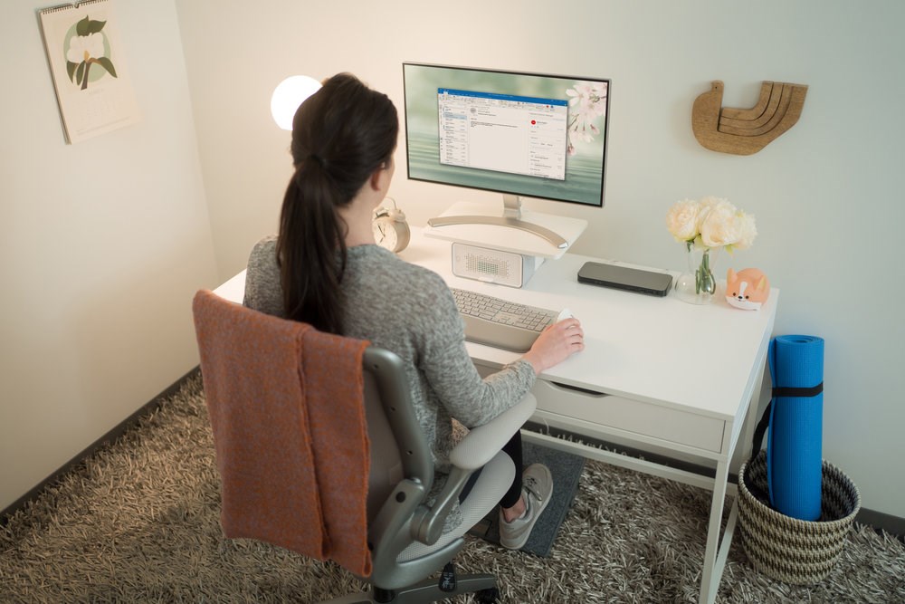 Woman working at a desktop monitor with an air purifier underneath