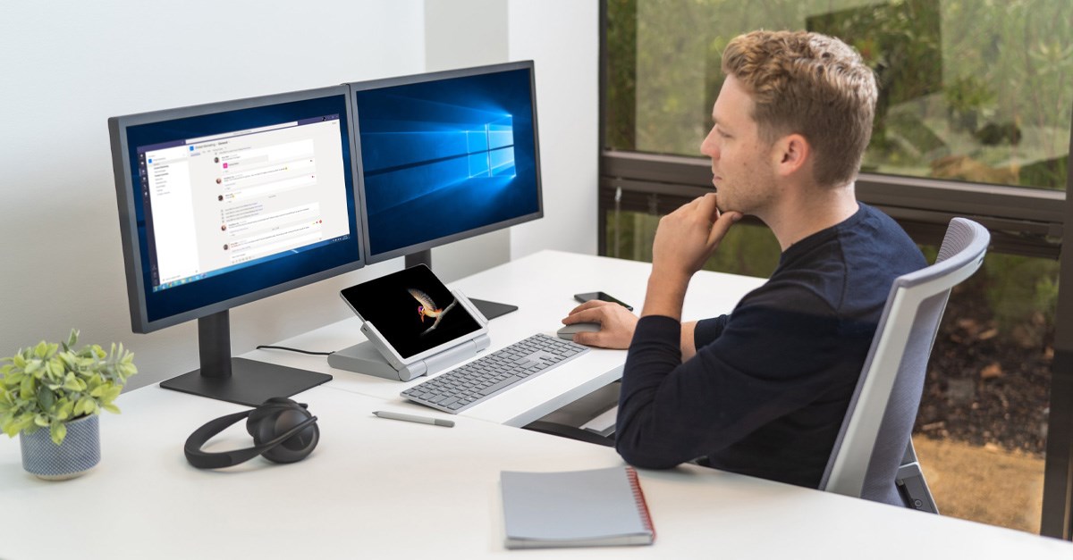 Man working at a computer desk with a tablet paired with a docking stand