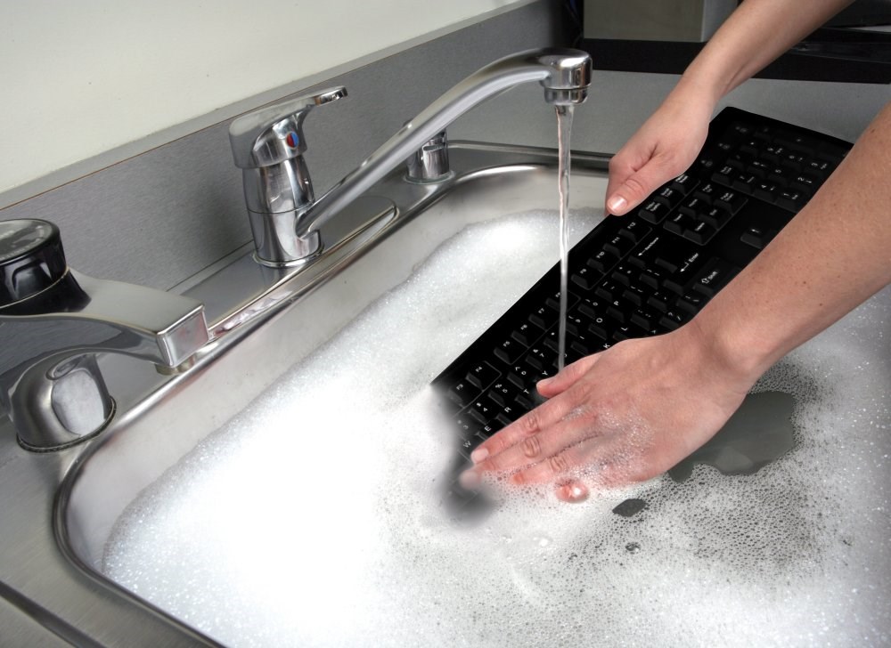 Person washing a Kensington Pro Fit® USB washable keyboard in a sink