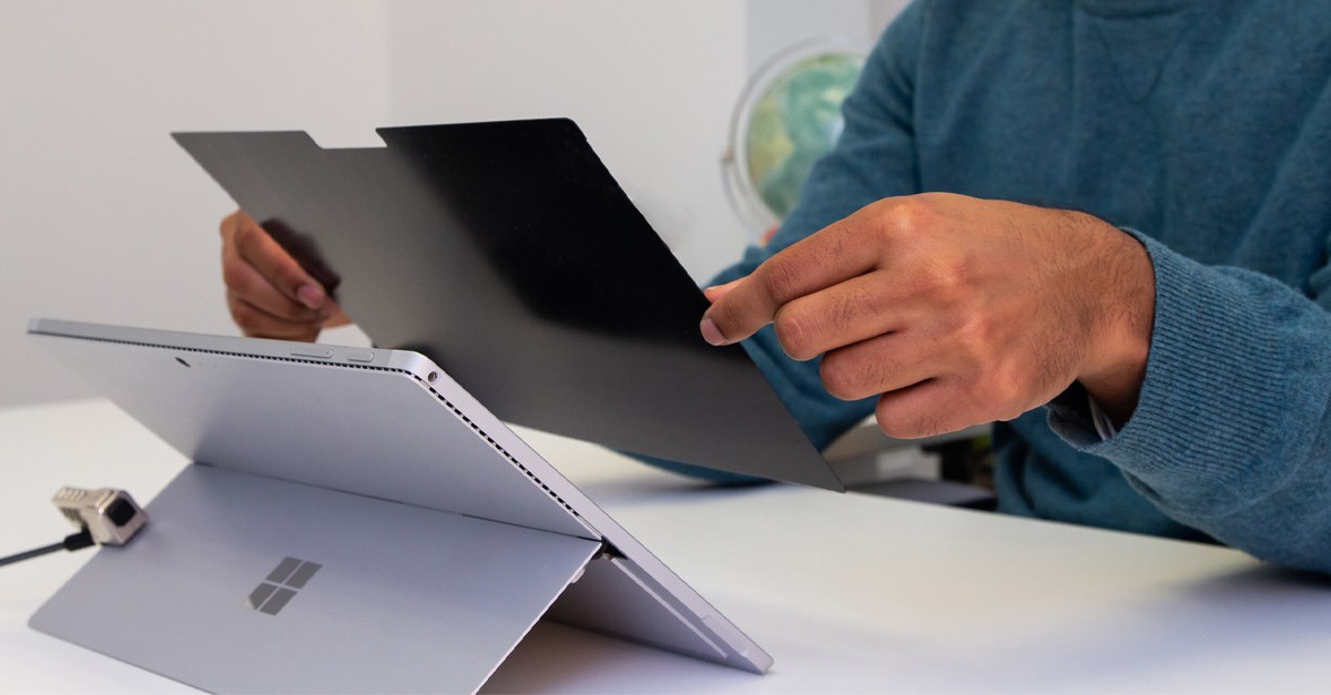 Person placing a privacy screen onto a Microsoft Surface tablet