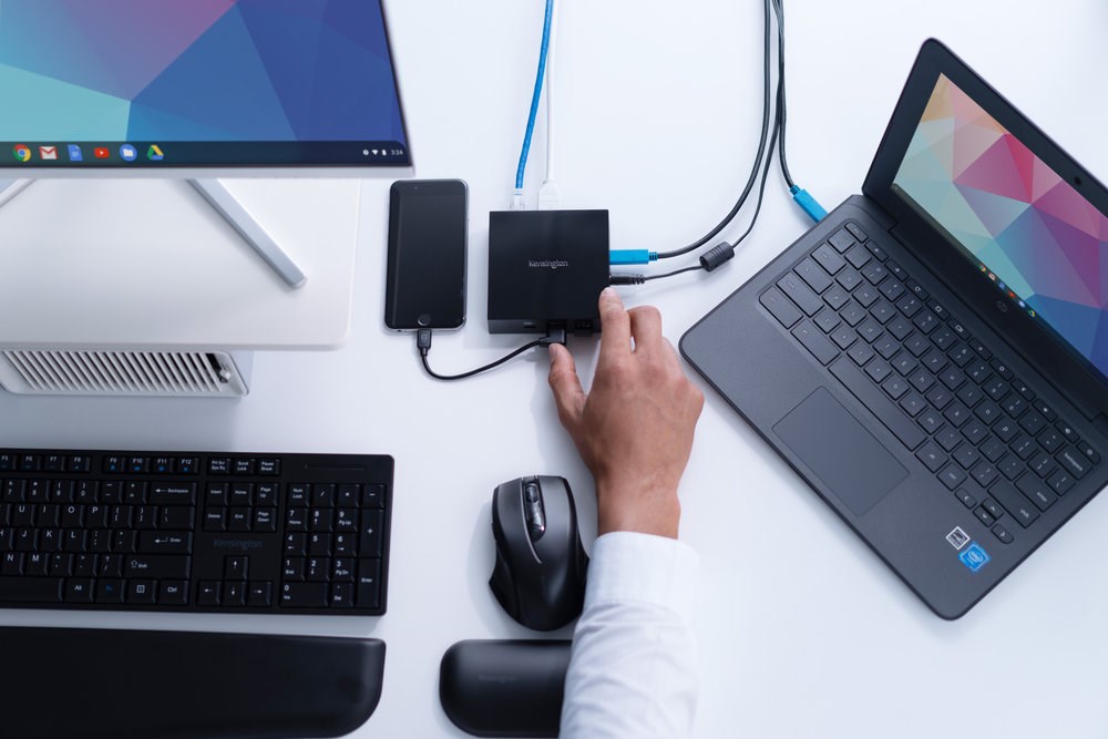 Person working at a monitor and laptop setup connected to a docking station