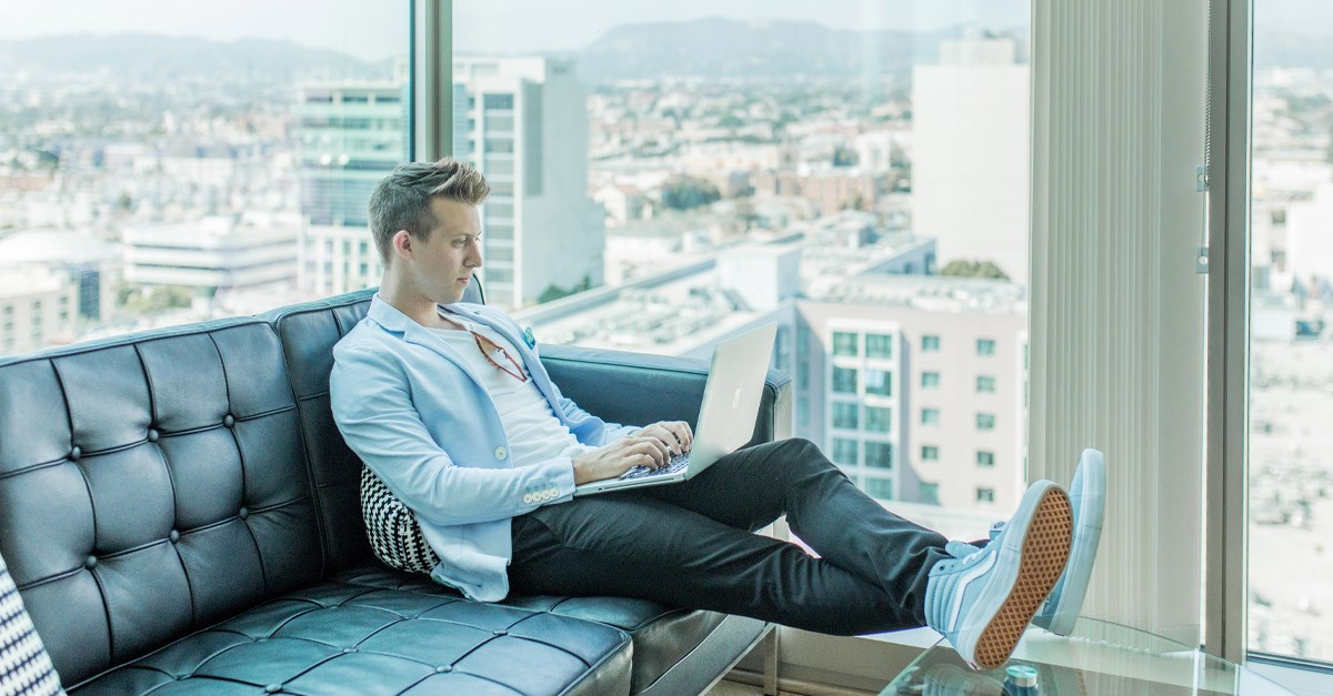 Man sitting on a couch working on a computer