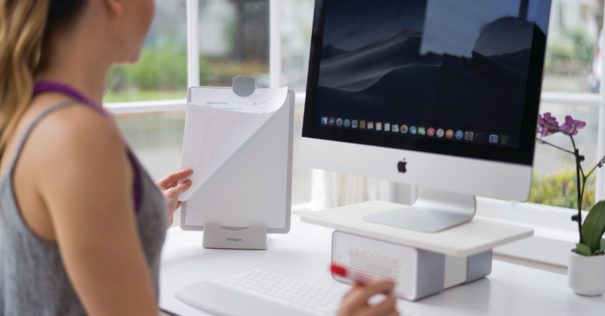 Woman working on an iMac computer and using a Kensington OfficeAssist™ Multi-Function Copyholder