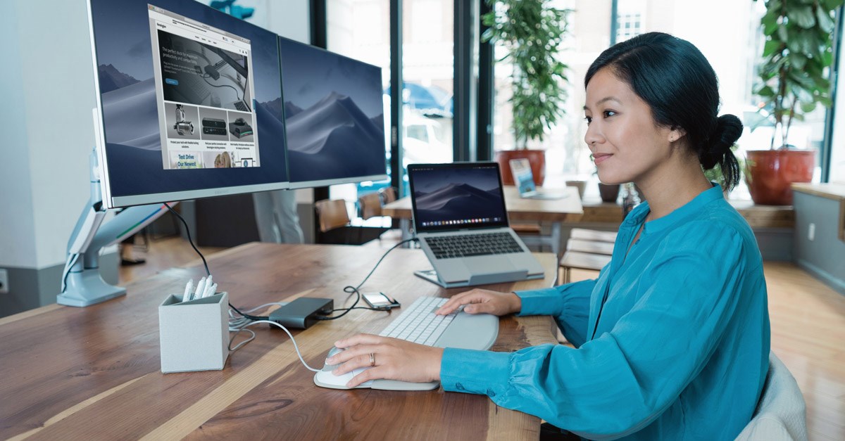 Woman working at a desktop computer connected to a Kensington monitor arm