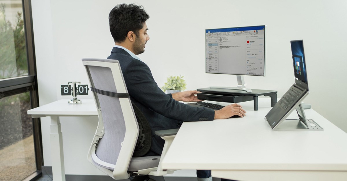 Man working at a desktop computer on a Kensington riser