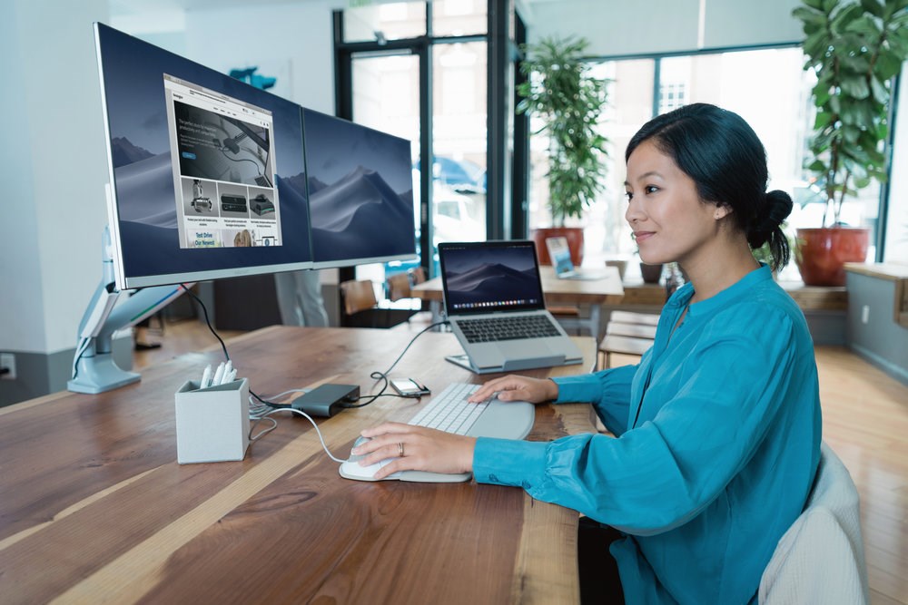 Woman working on a desktop connected to a monitor arm and docking station