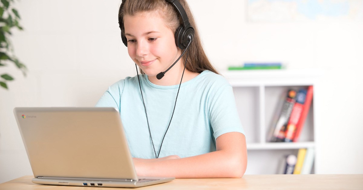 Child wearing a headset with a microphone and working on a laptop