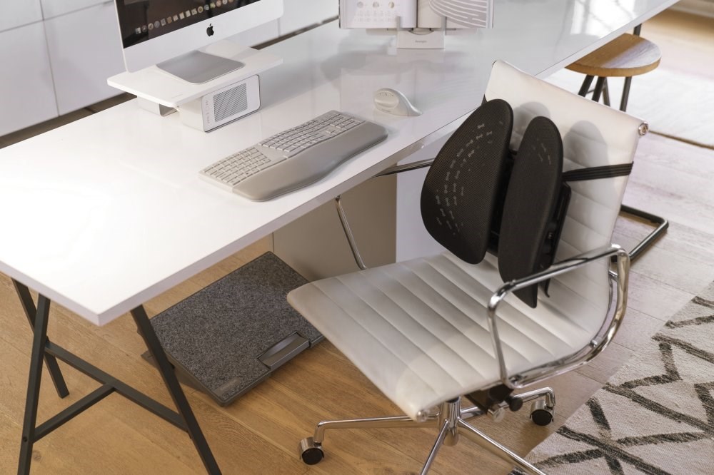 Ergonomic home office setup with a desktop riser, a book stand, back support, keyboard, and mouse