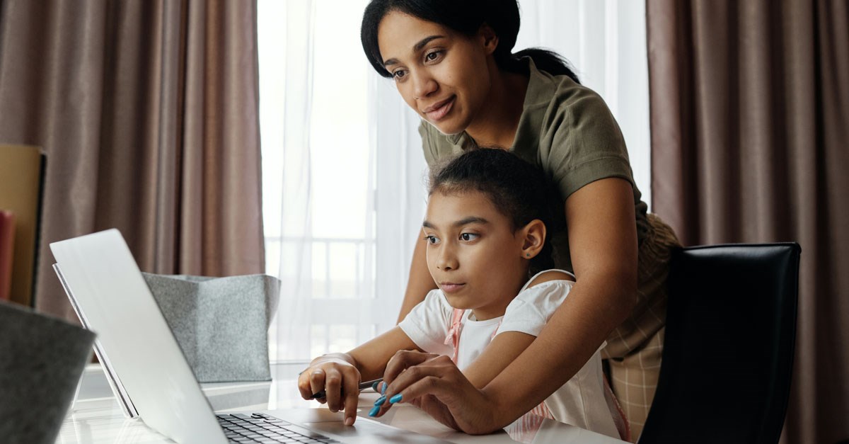 Mother helping a child on a laptop