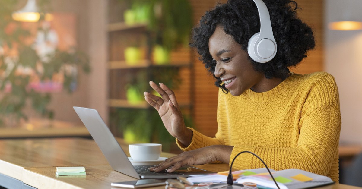 Woman smiling and working at a laptop with headphones on