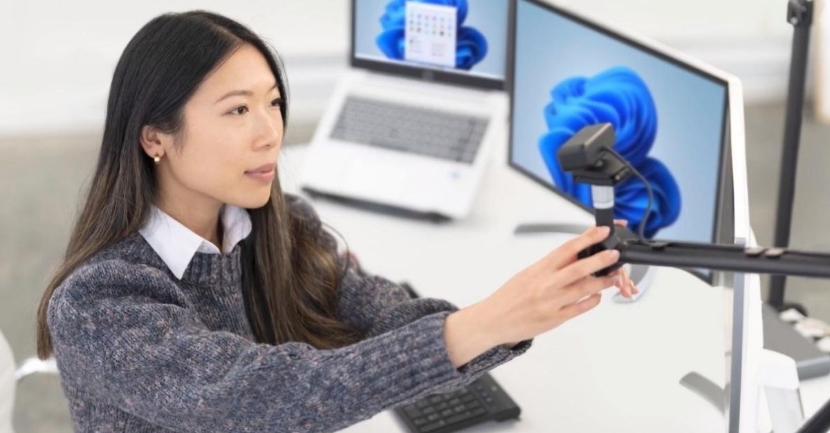 Une femme prépare sa table et son équipement pour un appel vidéo. 