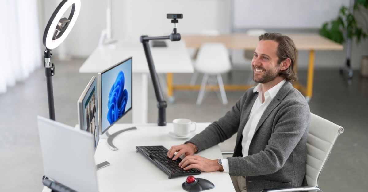 hombre sentado frente a computadora tomando una videoconferencia con equipo Kensington