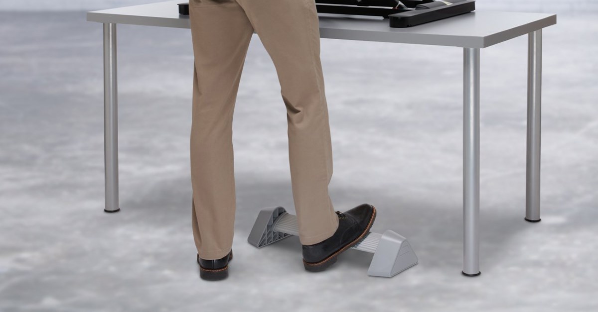Person standing at desk using Kensington foot rest