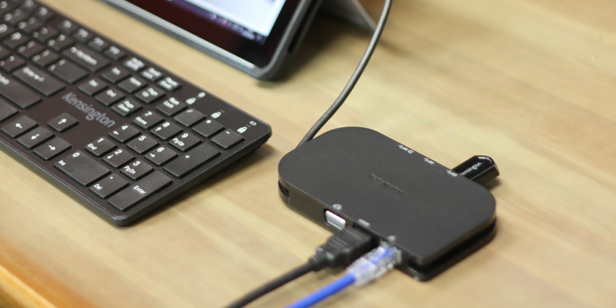 Close up to a Kensington Docking Station and Keyboard over a wood desk 