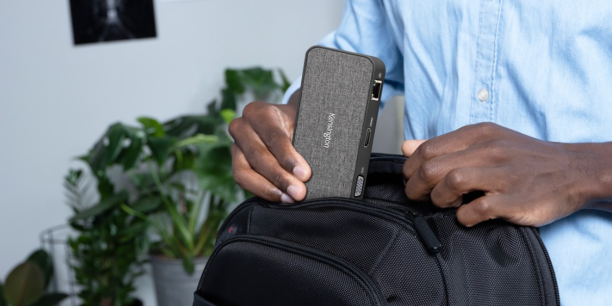 A person putting a Kensington Docking station in his backpack