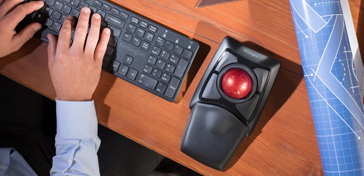 Kensington Expert wireless trackball on a wooden desk, next to some blueprints