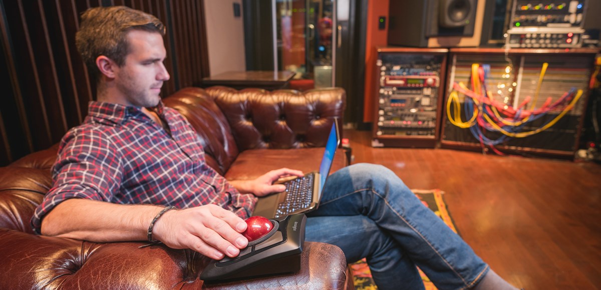 Man working with a Kensington Expert Wireless Trackball seated on a couch