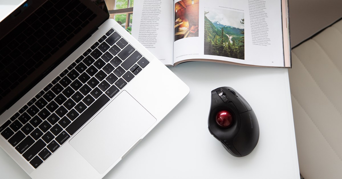 Pro Fit® Ergo Vertical Wireless Trackball on a white desk next to a MacBook.