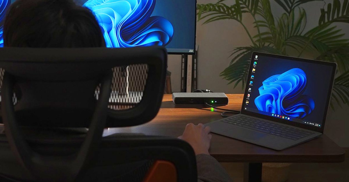 Person sitting at desk with a laptop connected to a Thunderbolt 4 docking station.