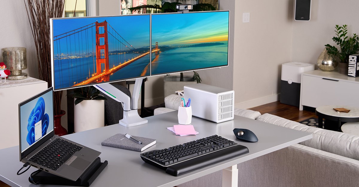 Desktop with dual monitors and professional video conferencing equipment from Kensington plus the new MK7500F QuietType mechanical keyboard.
