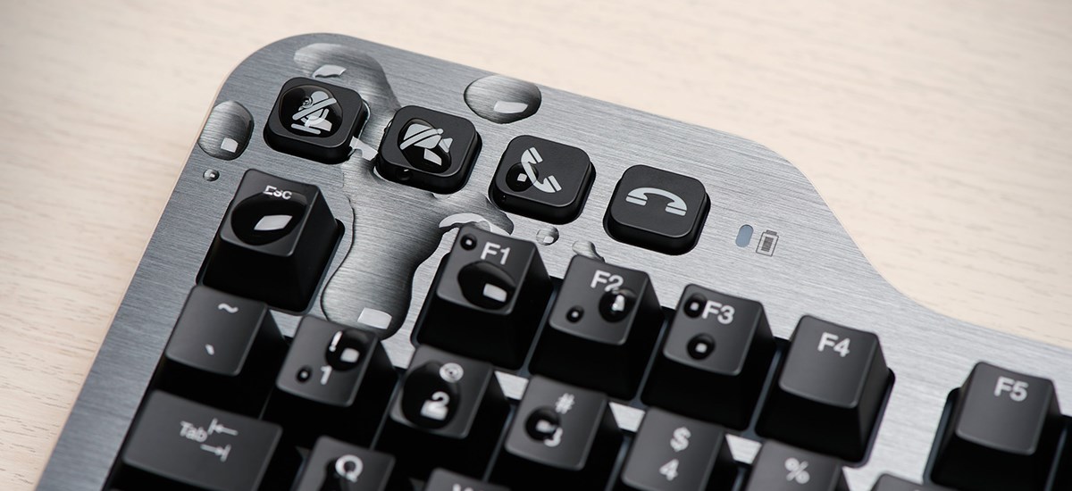 Kensington Mechanical Keyboard keys splashed with water on a wooden desktop.