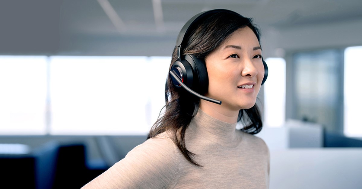 Woman in an office using Kenisngton h300 wireless headphones on a call.