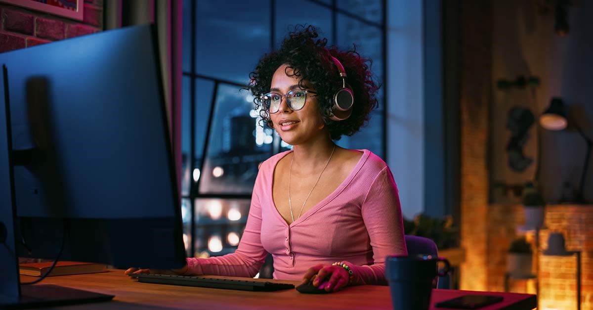 woman working at a computer with bright lights and headphones.